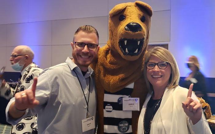 Woman and man stand with NIttany Lion mascot